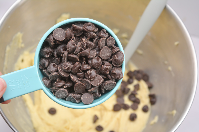 a scoop of chocolate chips over a mixing bowl