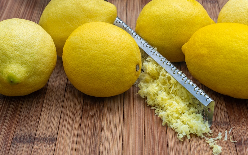 lemons and a zester on a wooden board