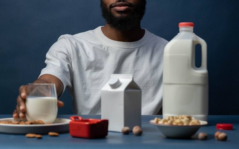 a man sitting with a bottle of almond milk and a cup