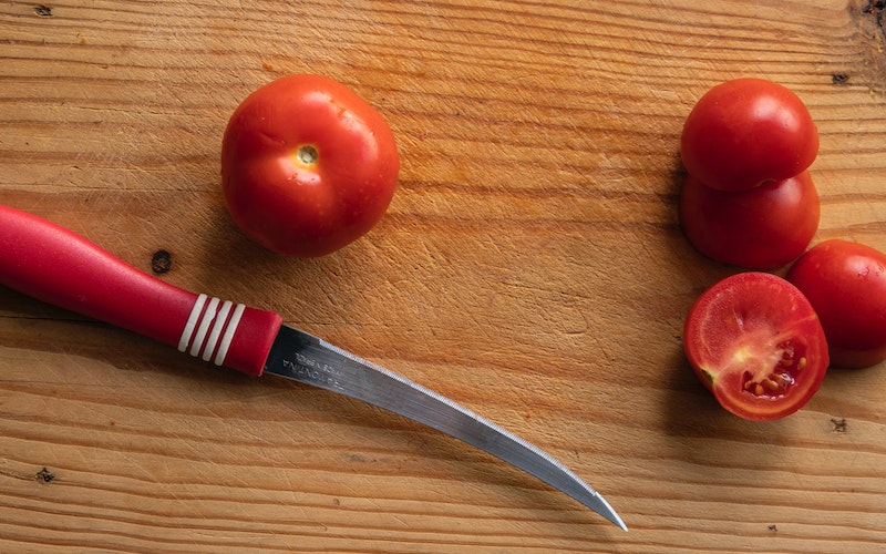 tomato on a cutting board with a knife