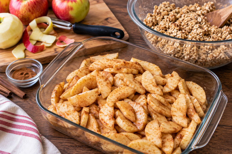 a baking pan of peeled apples with topping in a bowl